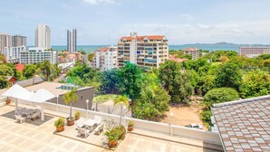 A rooftop terrace with outdoor seating, potted plants, and a view of the cityscape and ocean. - 1 Bedroom 716 High Floor Seaview (Pattaya)