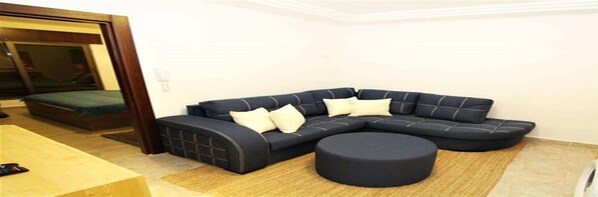 Una sala moderna con un sofá modular, un taburete redondo y una pequeña mesa.