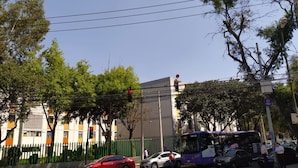 Escena callejera con un coche rojo, un autobús morado y un coche blanco en una intersección.