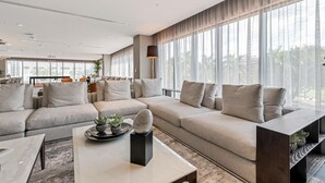 Una sala de estar moderna con un amplio sofá modular, una mesa de centro y un comedor al fondo.