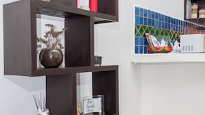 Un meuble d’angle en bois foncé à plusieurs niveaux, agrémenté de divers objets décoratifs, une horloge au mur et un pare-éclaboussures carrelé.