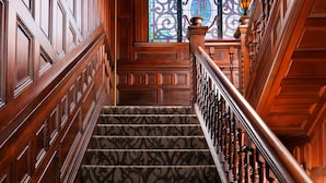 A grand staircase with a patterned carpet, wooden balustrade, and a stained glass window at the top. - Pendray Inn & Tea House (Victoria)