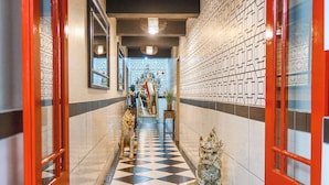 A hallway with a checkered floor, a statue of a lion, and a red door. - 55 on Main Guesthouse and Spa (Cape Town)