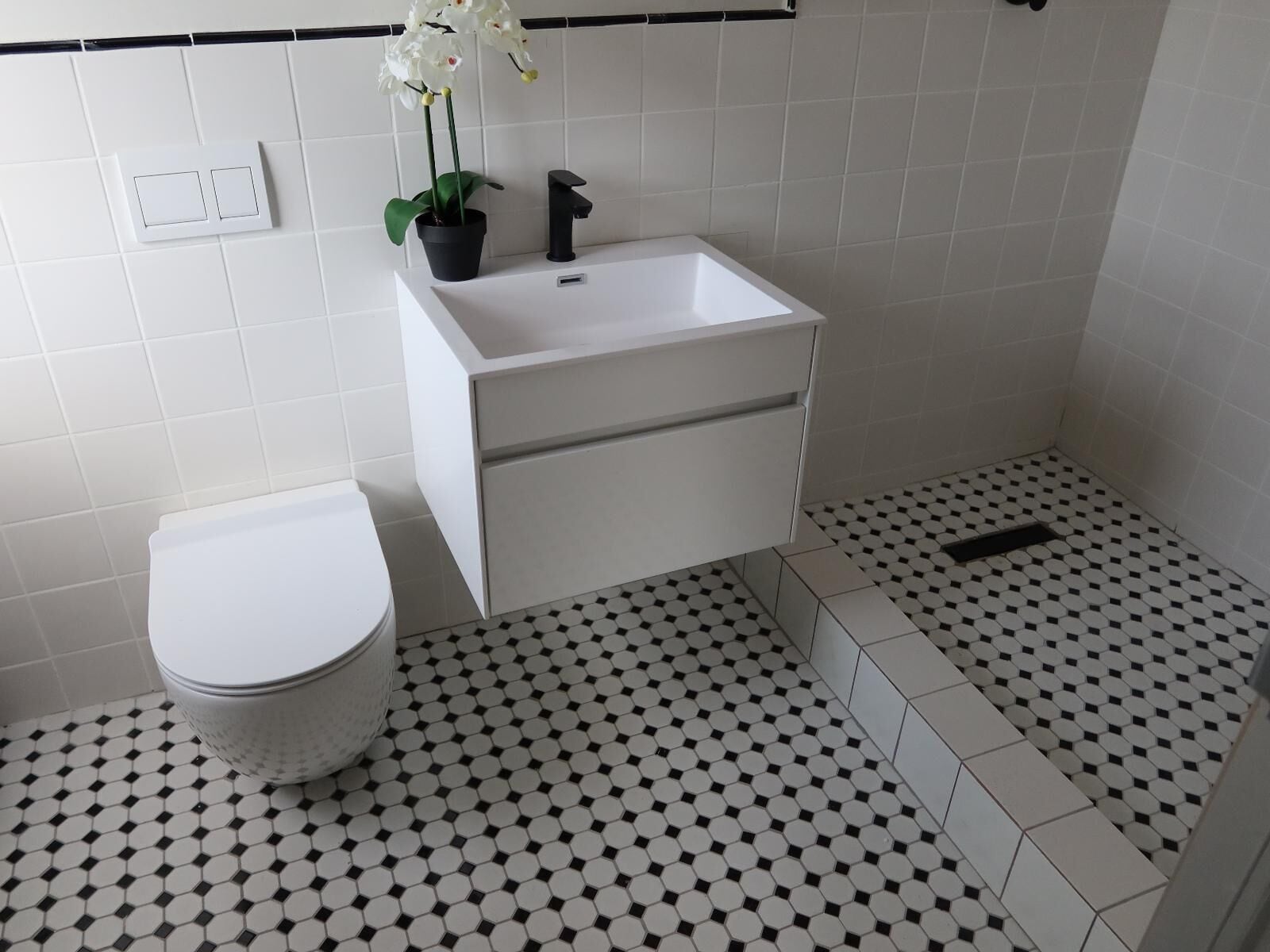 A bathroom with a white sink, a toilet, and a shower area.