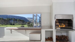 Una cocina moderna con una parrilla integrada, vista a un campo de golf y una montaña al fondo.