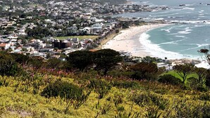 Un pueblo costero con playa, casas y montañas al fondo.