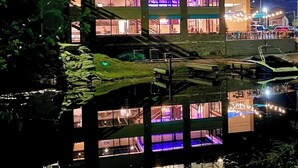 Een meerlaags gebouw met balkons, een parkeersbord en een weerspiegeling in het water.