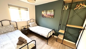 A bedroom with two beds, a wardrobe, and a painting on the wall. - Horizon Apartments (Southampton)