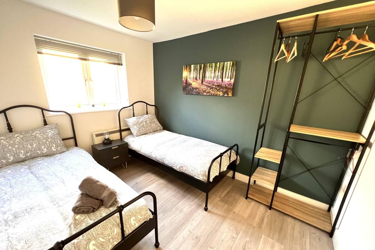 A bedroom with two beds, a wardrobe, and a painting on the wall.