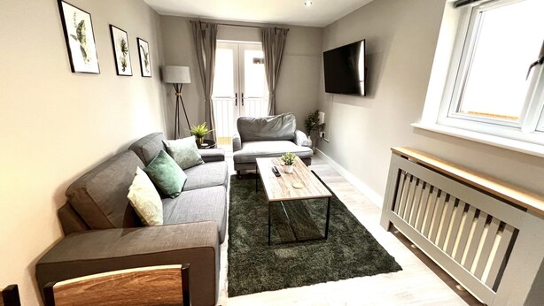 A modern living room with a sofa, a coffee table, and a TV mounted on the wall. - Horizon Apartments (Southampton)