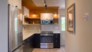 Une cuisine moderne dotée d’appareils électroménagers en acier inoxydable, de planchers en bois et de luminaires suspendus.