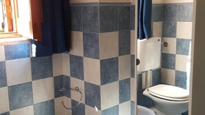 A bathroom with a tiled floor and walls, a toilet, and a shower area with a curtain. - Addaura Sea, Villa Opposite the sea (Palermo)