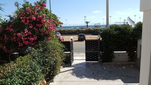 Un vialetto recintato che conduce a un'area di parcheggio con vista sul mare.