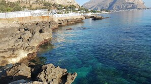 A coastal area with rocky cliffs, clear blue water, and a white fence along the shore. - Addaura Sea, Villa Opposite the sea (Palermo)