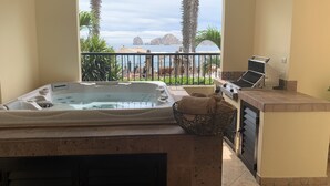 Ein Badezimmer mit Badewanne, Handtuchhalter und Blick auf Pool und Palmen.