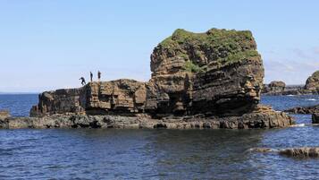 A rocky coastal landscape with three people standing on a cliff.