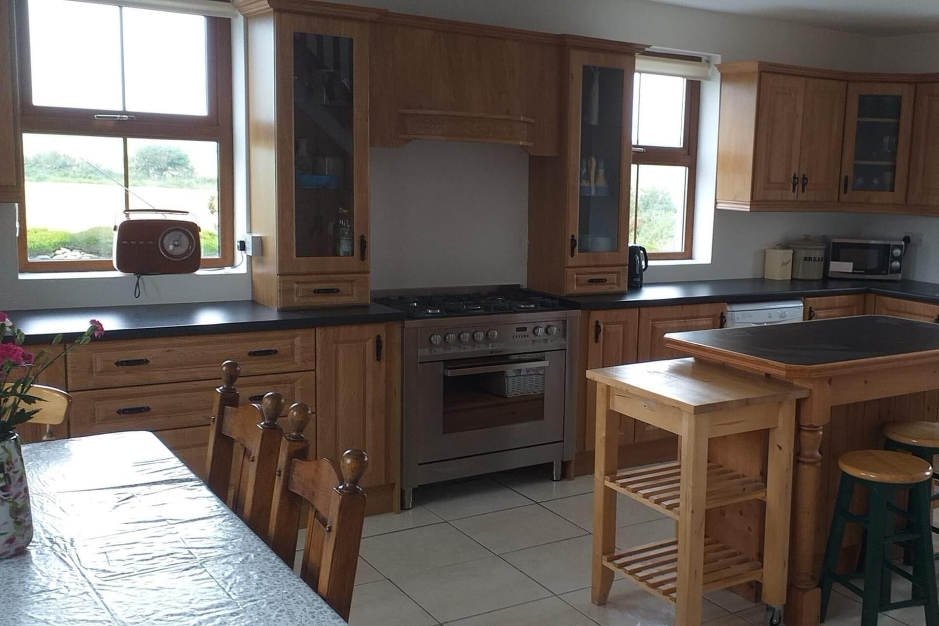 A kitchen with wooden cabinets, a stove, a microwave, and a dining table with chairs.