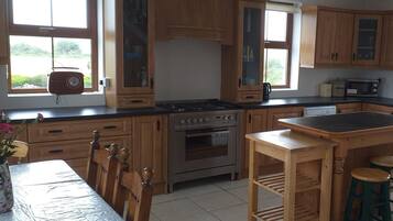 A kitchen with wooden cabinets, a stove, a microwave, and a dining table with chairs.