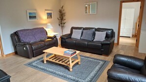Ein Wohnzimmer mit zwei Ledersofas, einem Holztisch und einem gemusterten Teppich.
