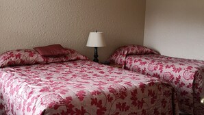 A hotel room with two beds, each with floral-patterned bedding, a bedside lamp, and a textured beige wall. - Kelowna Timeshare July Rental for 1 Week (Kelowna)