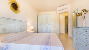Ein Schlafzimmer mit einem Bett, einer Kommode, einem Spiegel und einer Tür zu einem anderen Raum.
