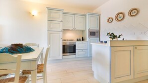 Cocina compacta con armarios blancos, un microondas y un comedor con mesa y sillas.