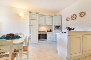 A compact kitchen with white cabinets, a microwave, and a dining area with a table and chairs.