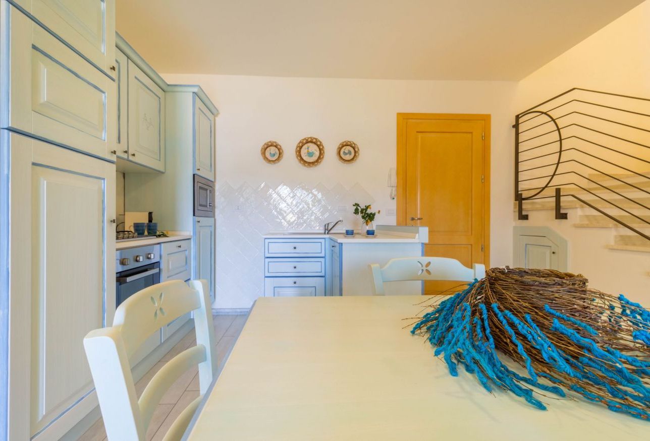 A kitchen with light blue cabinets, a wooden door, and a decorative wall piece.