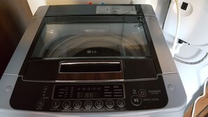 Vista frontal de uma máquina de lavar inteligente LG Smart Inverter, com visor digital, painel de controle e porta transparente.
