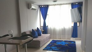 A modern living room with a sofa, a coffee table, and a bar area with stools. - Excellent Apartment With the Best Location in the City (Cali)
