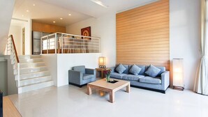 Un salon moderne avec un escalier, un ensemble de canapés et une table basse.