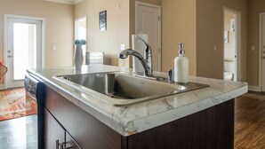 A kitchen with a large island, stainless steel sink, and a ceiling fan. - Sandia Peak Apartments by Frontdesk (Albuquerque)