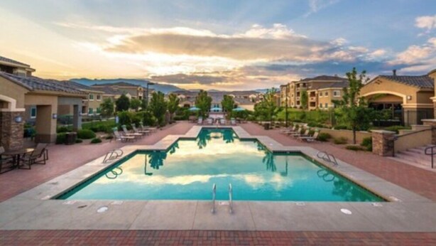 A swimming pool with lounge chairs and a view of surrounding buildings. - Sandia Peak Apartments by Frontdesk (Albuquerque)