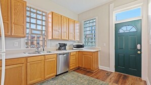A kitchen with wooden cabinets, a dishwasher, a coffee maker, and a microwave. - Indy Stadium Villas 707 (Indianapolis)