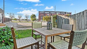 An outdoor patio with a wooden table and chairs, a lantern, and a view of a building in the background. - Indy Stadium Villas 707 (Indianapolis)