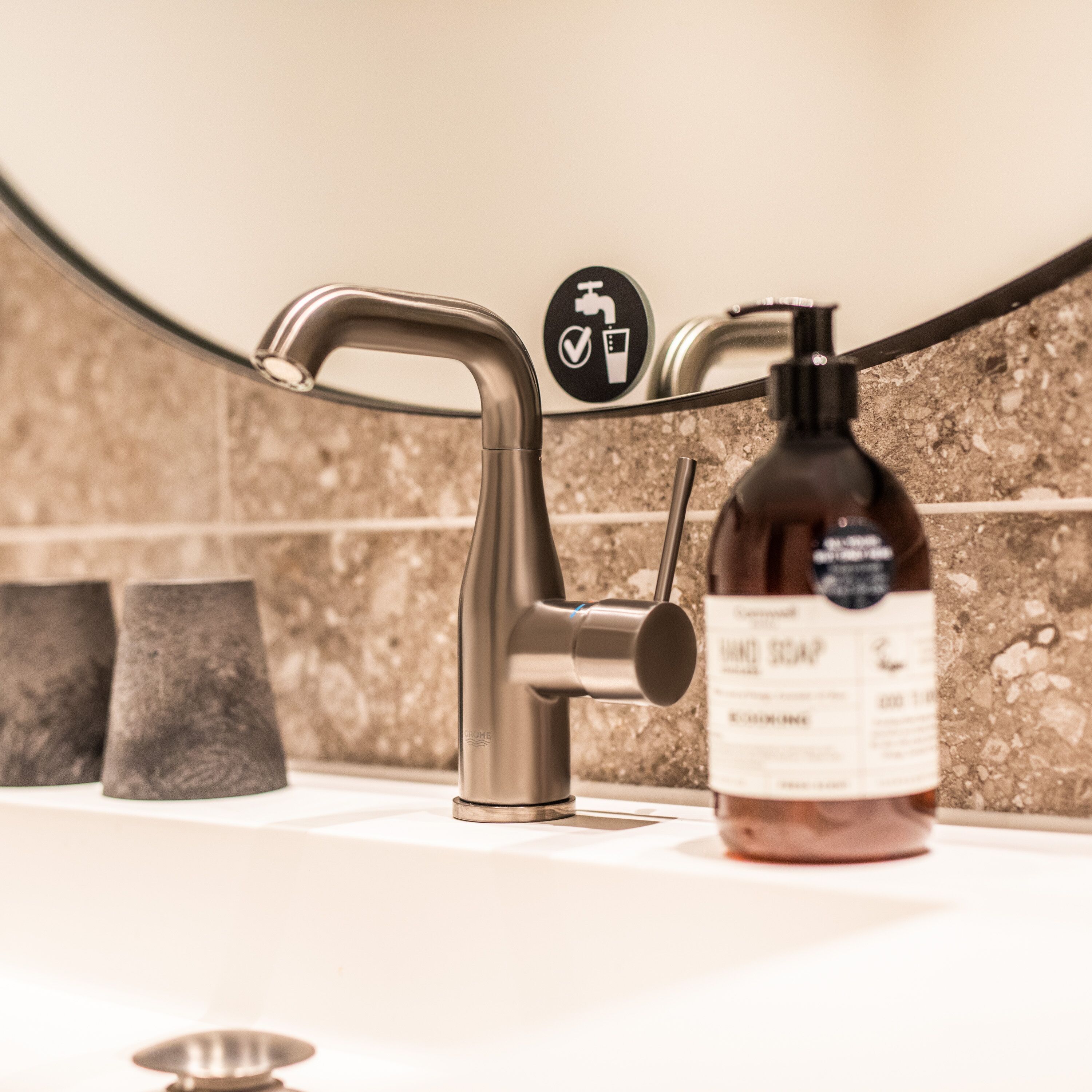 A bathroom sink with a modern faucet, a soap dispenser, and a hand soap bottle.
