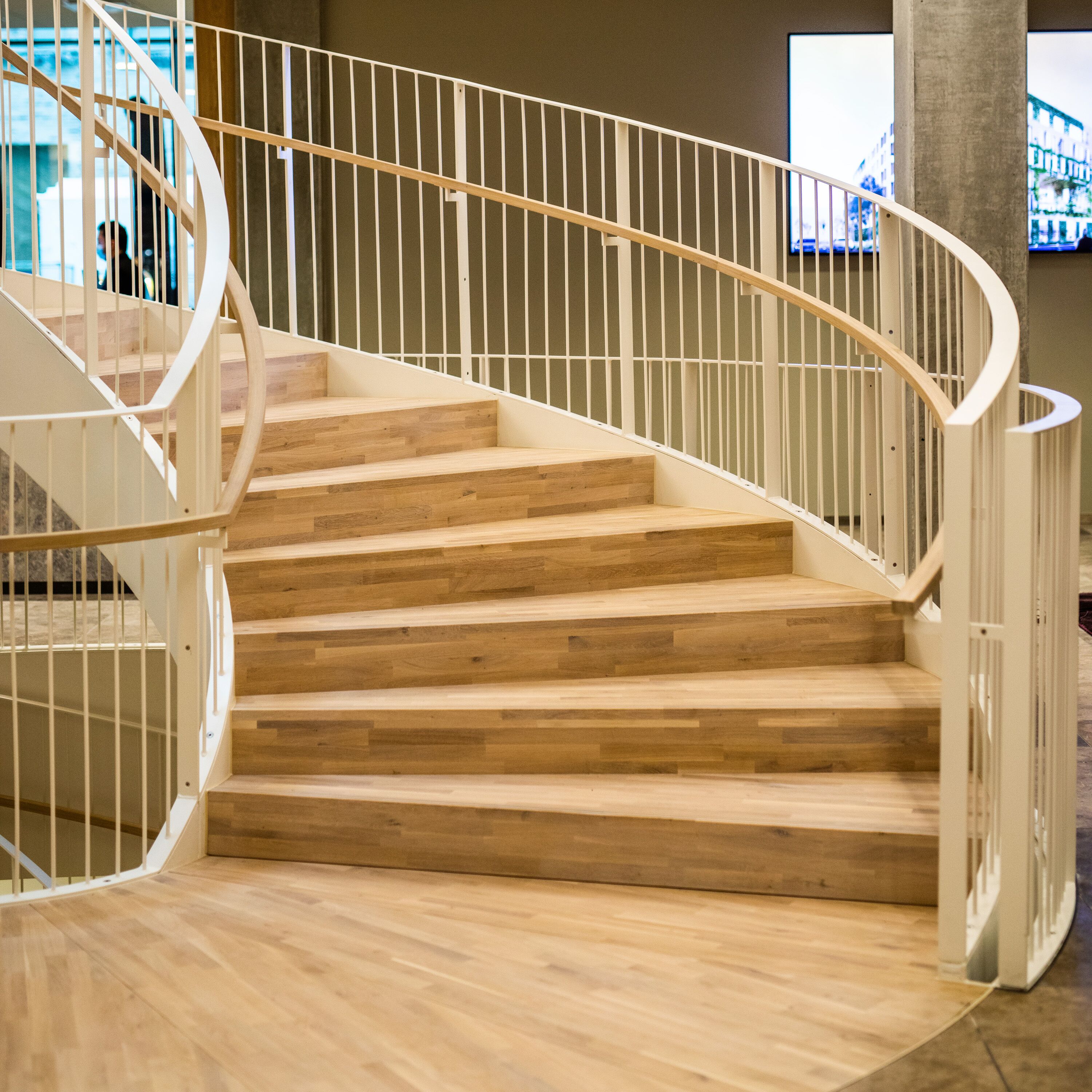 A spiral staircase with wooden steps and white railings in a modern interior.