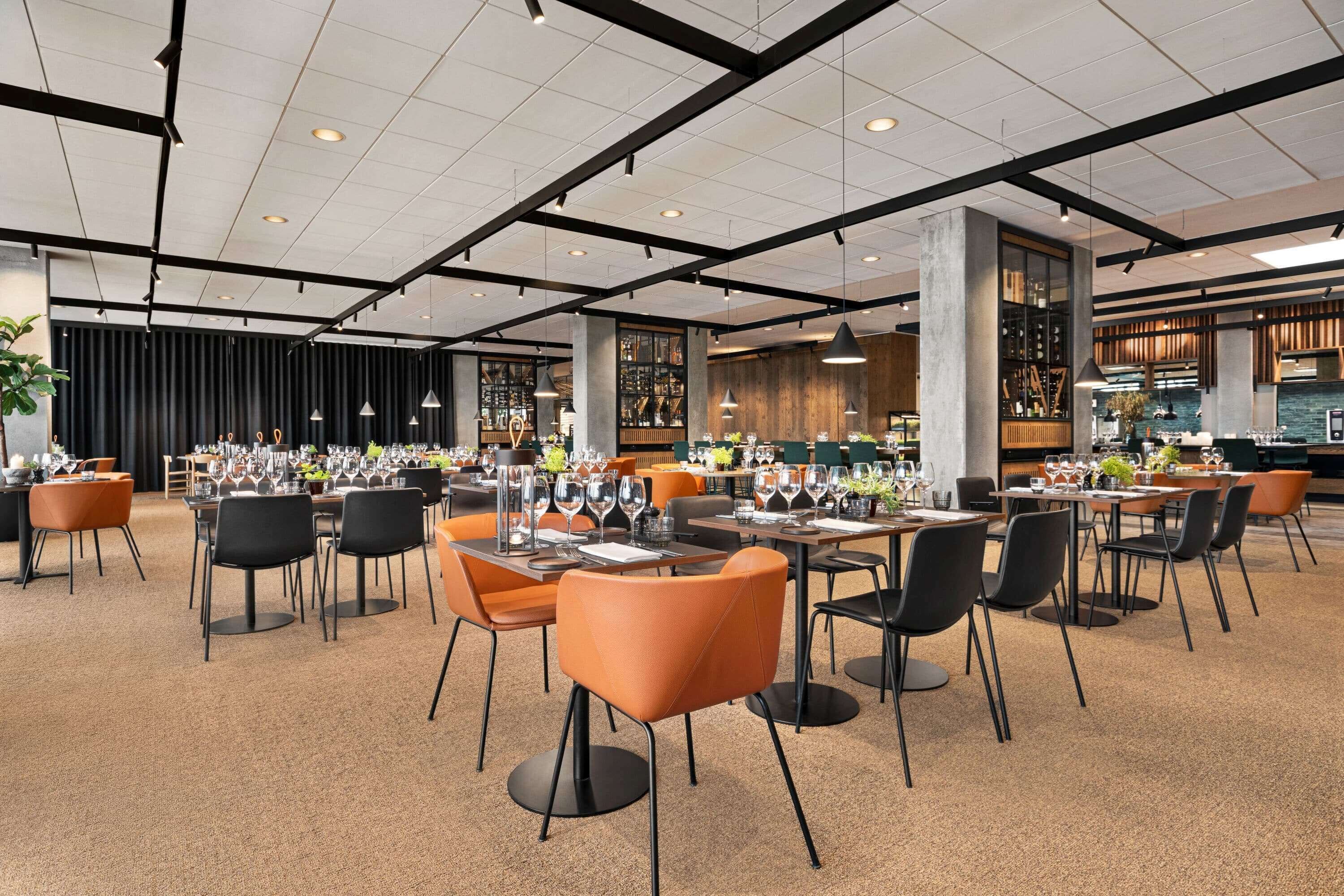 A spacious restaurant with multiple tables and chairs, a high ceiling with exposed beams, and a modern interior design.
