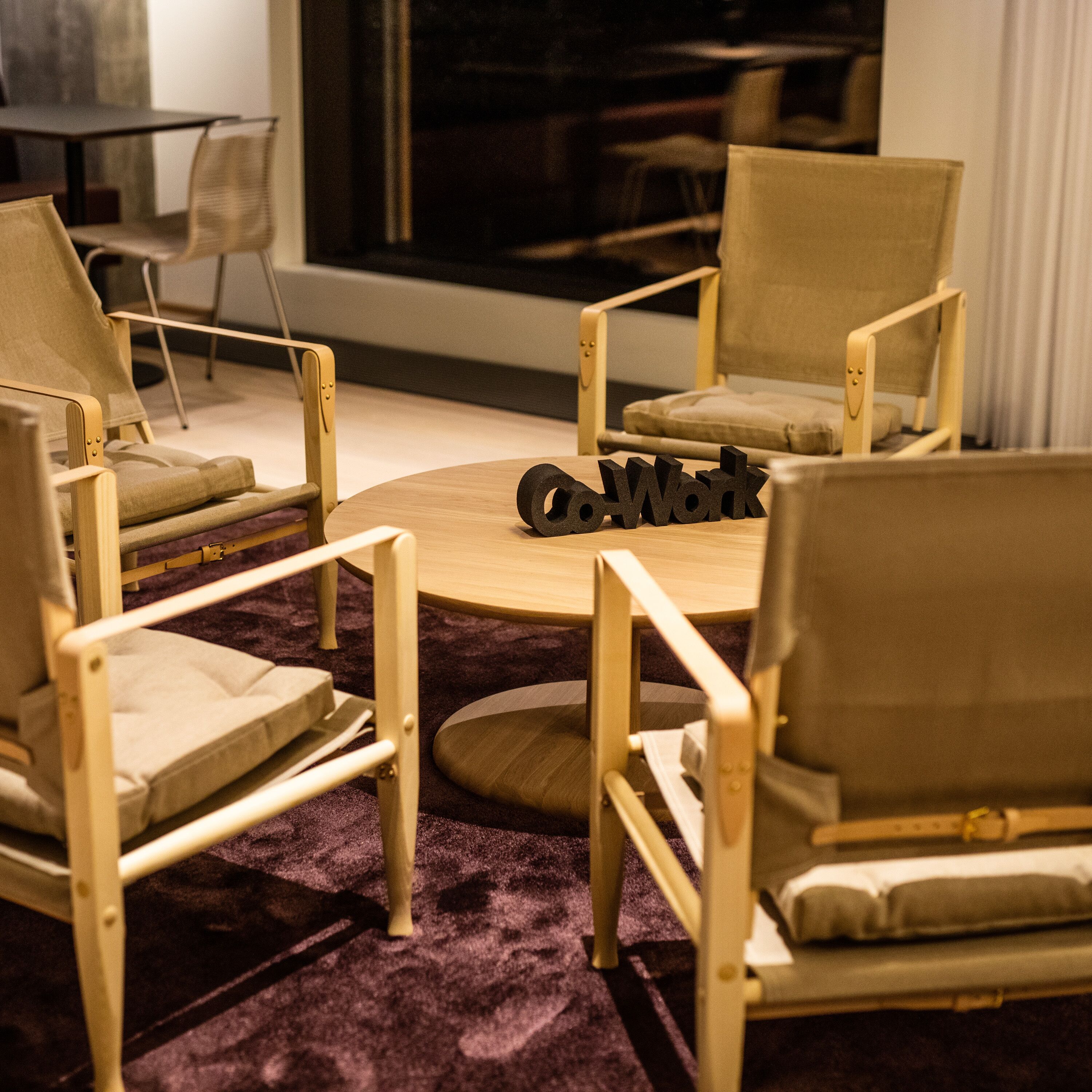 Una habitación moderna con sillas de madera y una mesa redonda.