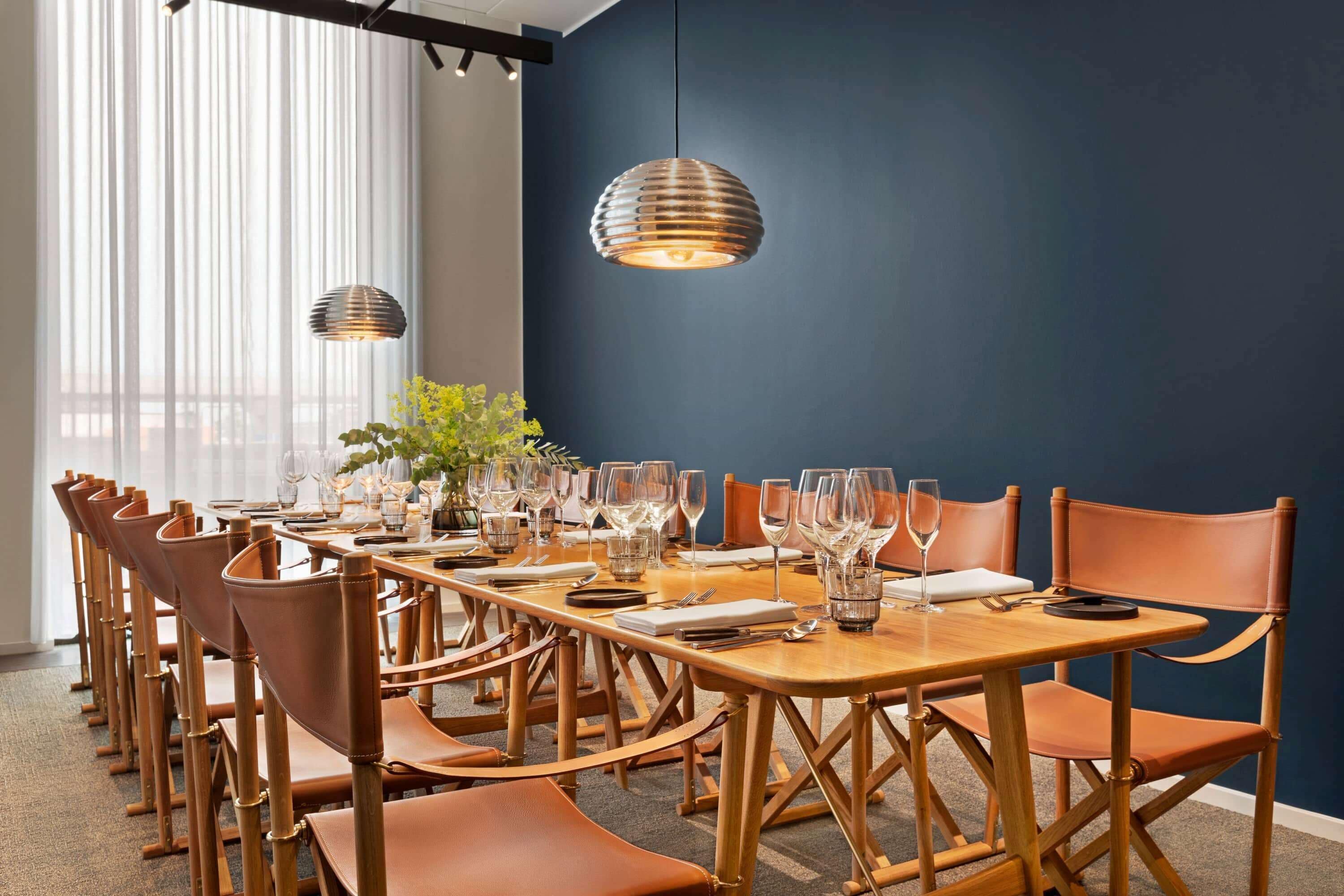 A conference room with a long table set for a meeting, surrounded by leather chairs.