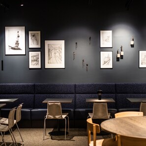 A restaurant interior with a dark wall, framed artwork, and seating arrangements. - Comwell Copenhagen Portside Dolce by Wyndham (Copenhagen)