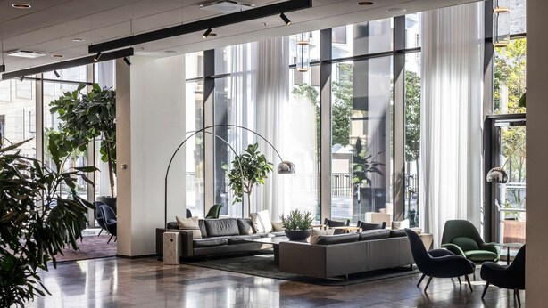 A spacious lobby with a modern sofa, chairs, and a large floor lamp.