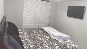 Cozy retreat with a bed, bedside table, and wall-mounted TV.