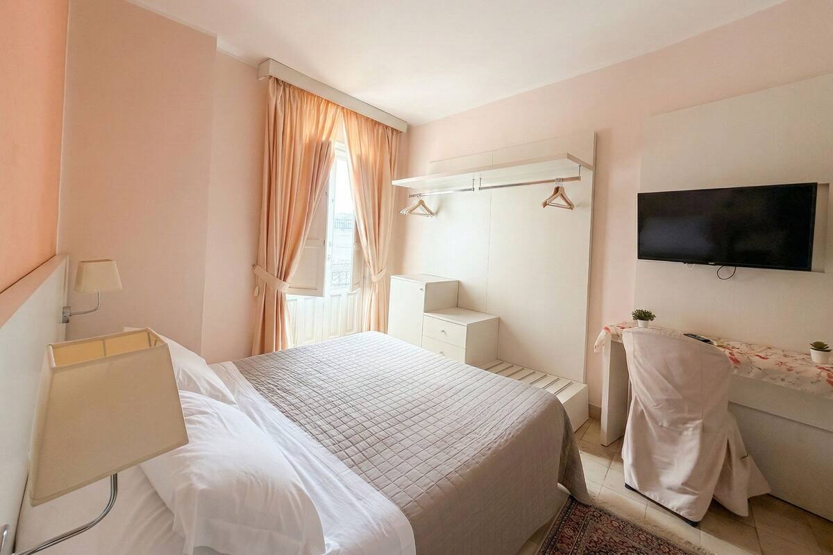 Een hotelkamer met een bed, een televisie, een bureau en een kledingkast.