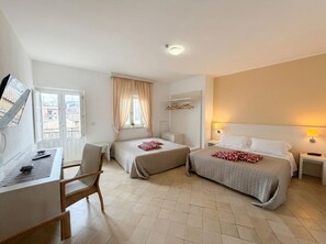 A hotel room with two beds, a desk, a chair, and a window with curtains.