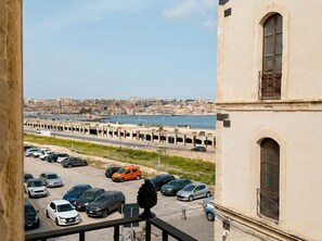 Une vue d’une ville côtière, avec un parking au premier plan et un bâtiment aux fenêtres en arc de cercle en arrière-plan.