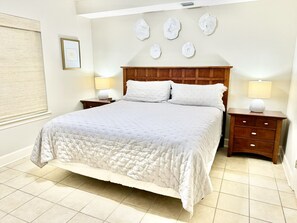A neatly made bed with a wooden headboard, two bedside tables with lamps, and a wall with decorative items.