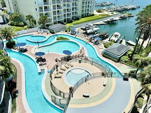 A resort with multiple swimming pools, a marina, and a large building with balconies.