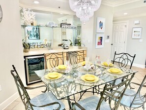A dining area with a glass table, metal chairs, and yellow plates.