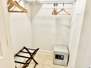 A small, white-walled room with a white cabinet, a wooden drying rack, and a metal rack with hangers.